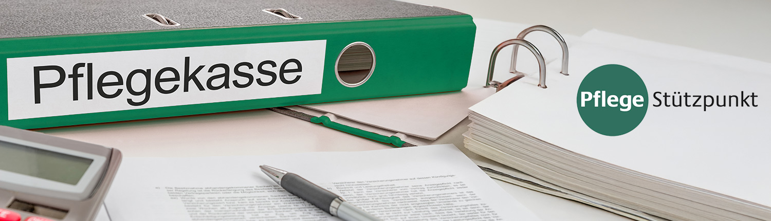 Ordner mit der Aufschrift „Pflegekasse“, Unterlagen und ein Stift auf einem Schreibtisch.
