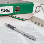 Ordner mit der Aufschrift „Pflegekasse“, Unterlagen und ein Stift auf einem Schreibtisch.