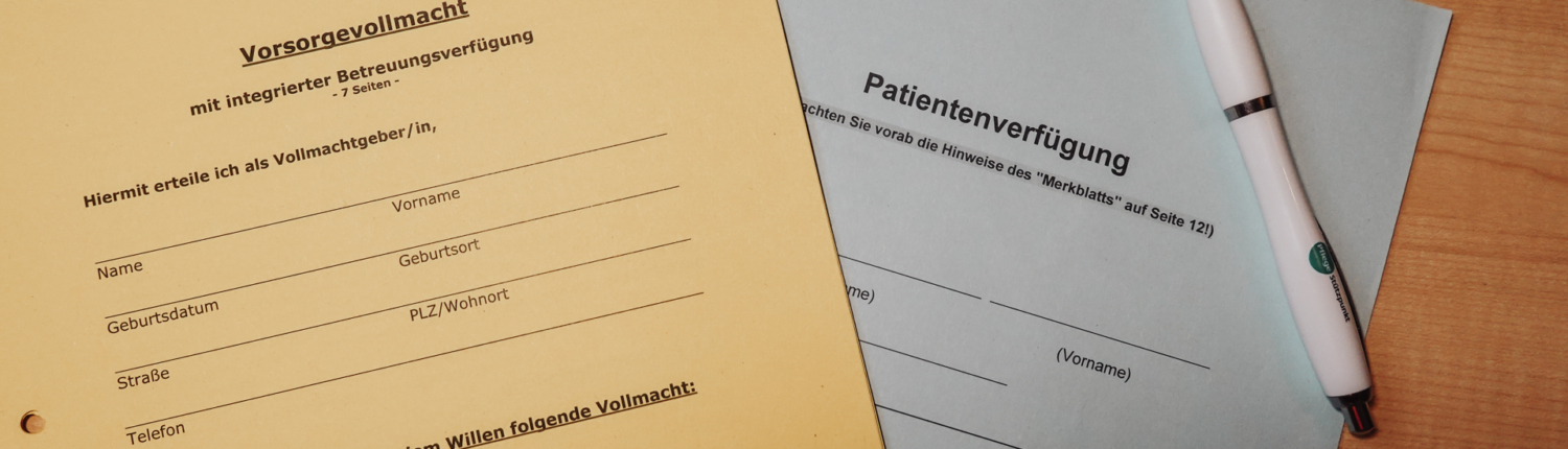 Formulare für Vorsorgevollmacht und Patientenverfügung liegen zusammen mit einem Stift auf einem Tisch.