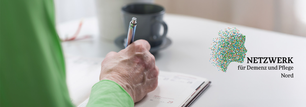 Ältere Person sitzt am Tisch und macht sich Notizen in einem Kalender.